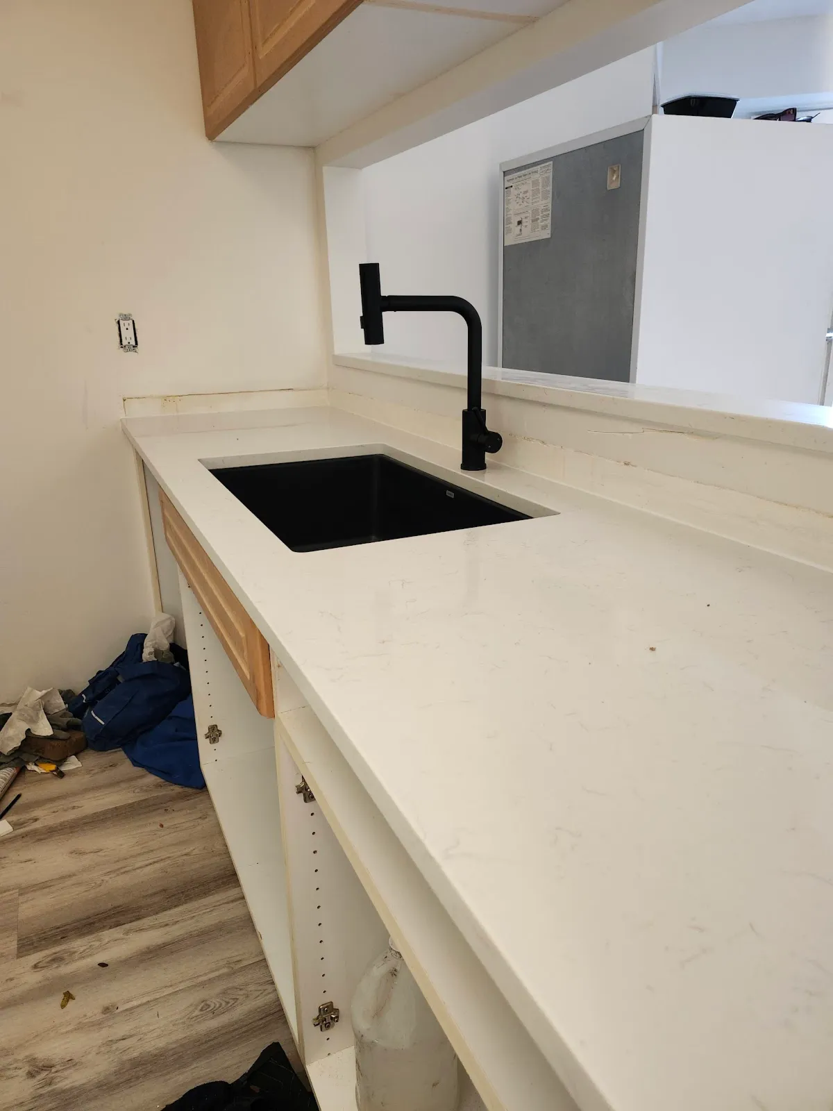 Black kitchen sink and matching faucet installed in a light stone countertop during an Apex Plumbing renovation